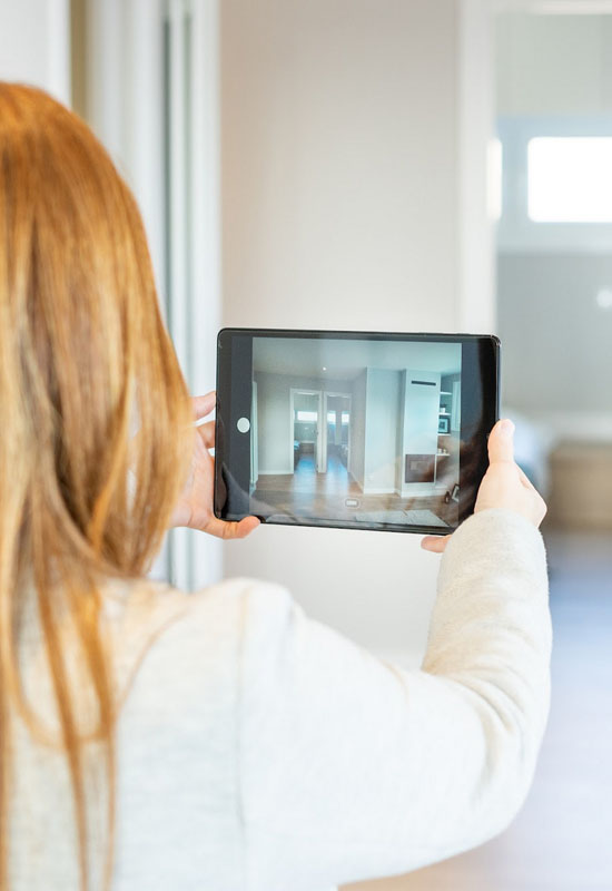 Jeune femme avec une tablette prenant des photos d'un appartement